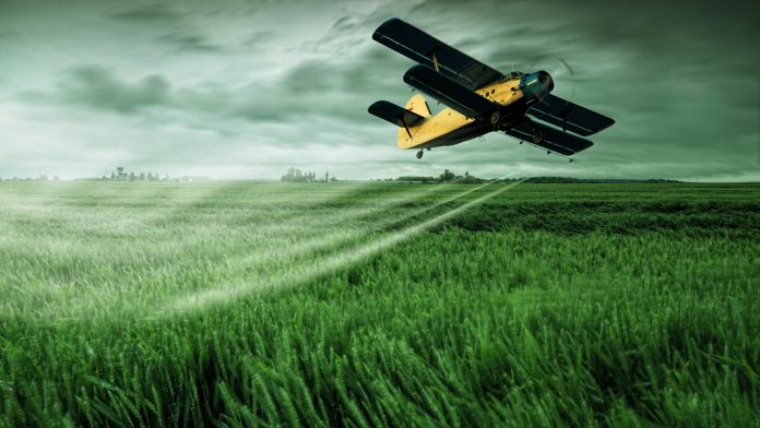 Letecký postřikovač kropí obilí pesticidy.