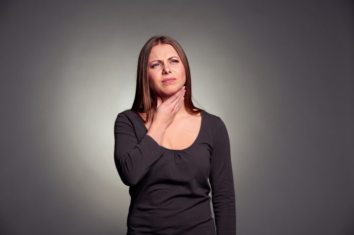 Žena s refluxem jícnu s bolestí v krku.